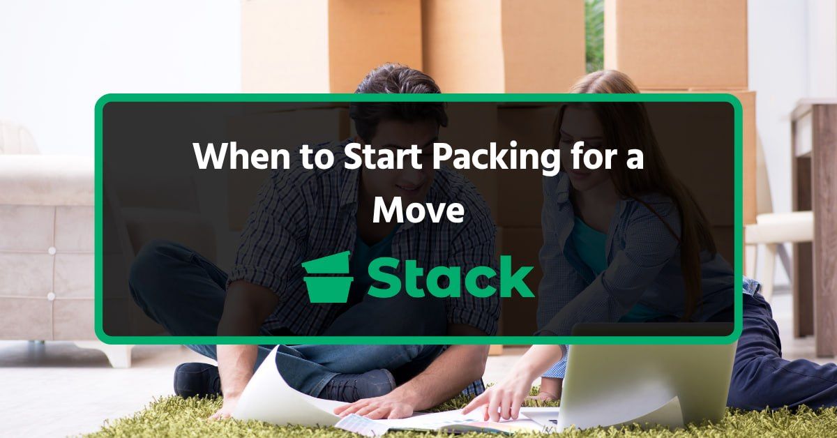 Couple sitting on the floor among moving boxes, planning when to start packing for a move