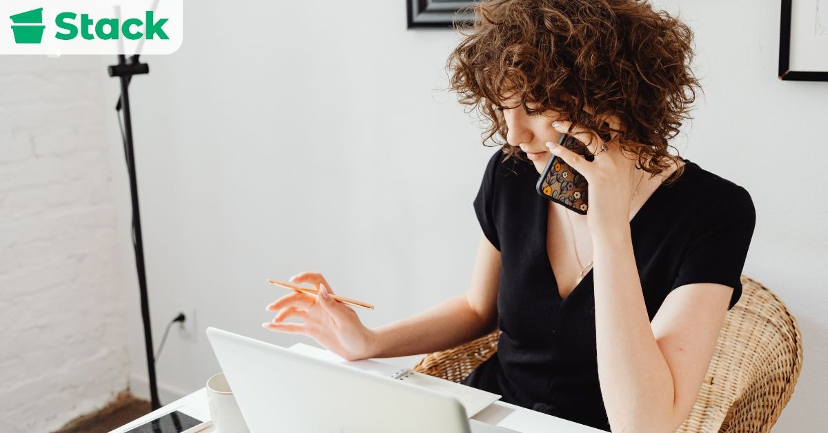 Professional coordinating an office move while working on a laptop and making phone calls during the final 1–3 months before moving day.