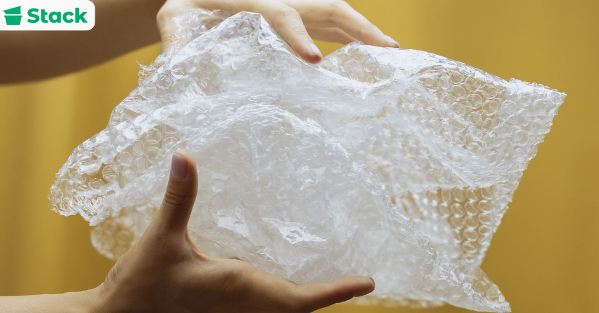 Hands holding a sheet of bubble wrap, one of the packing supplies used to protect fragile items during a move
