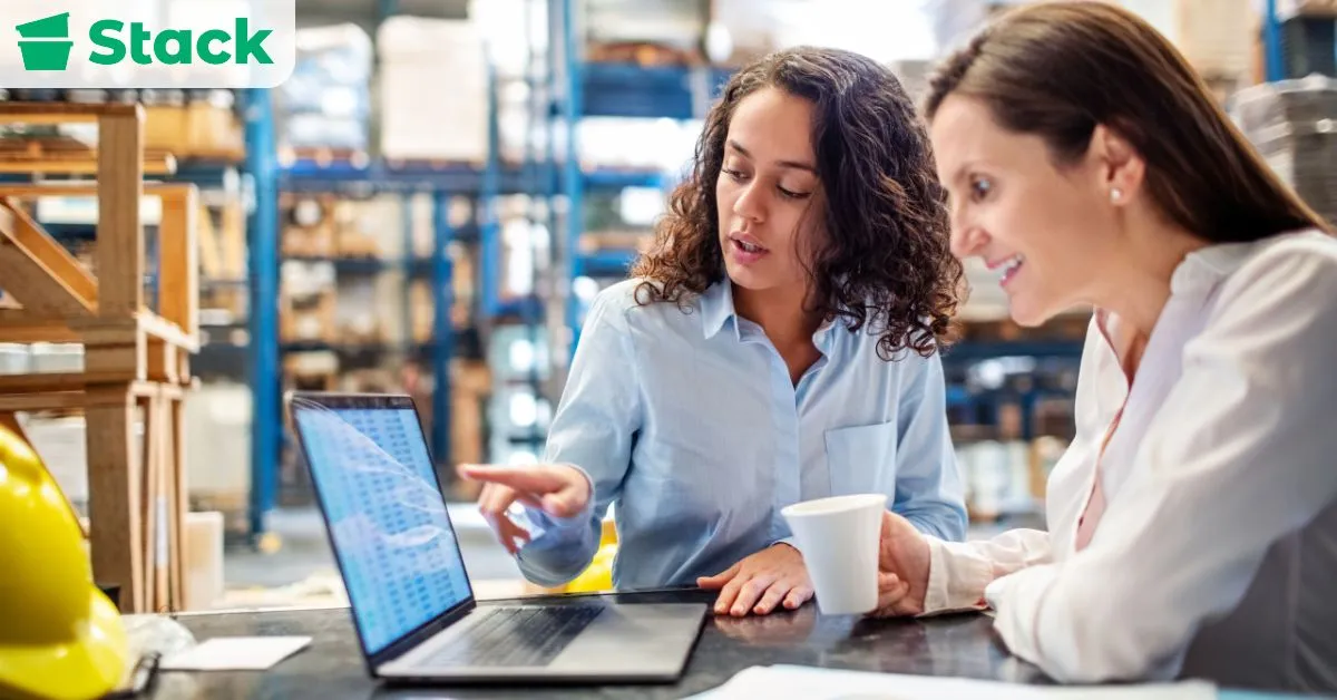 Office employees reviewing packing plans on a laptop while preparing inventory for an organized office move.