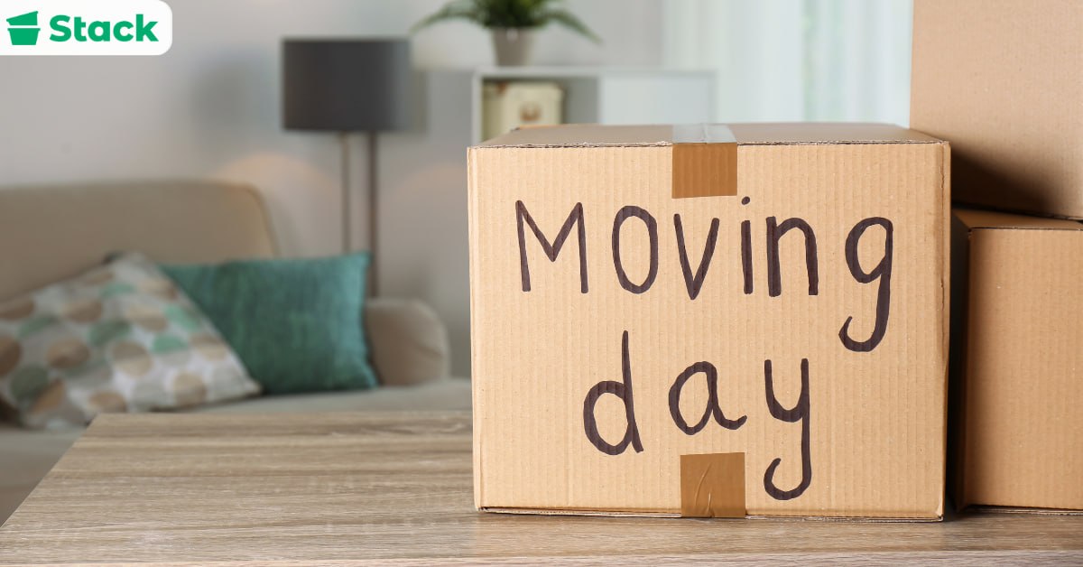 Cardboard box handwritten with the words Moving day, packed and set aside in a living room ahead of the move