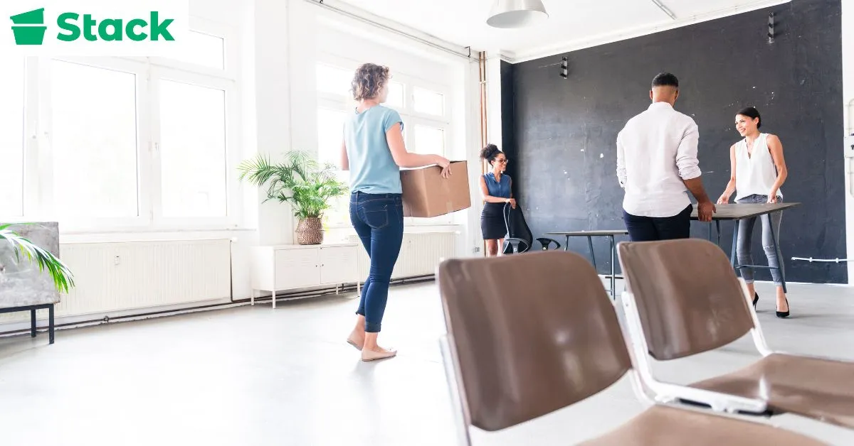 Office employees setting up furniture and workstations in a new office space after moving day.