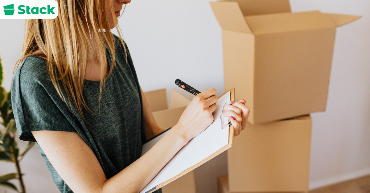 Person reviewing a list for moving out with packing supplies on table